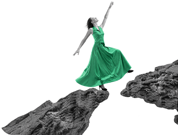 A woman in a green dress stepping across a gap between rocks