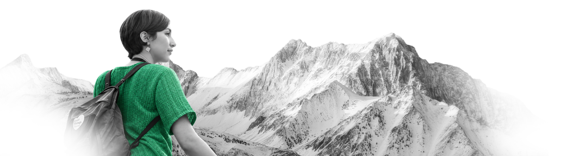 A hiker looking out over a snow-covered mountain range